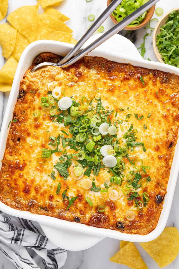 a white casserole dish filled with cheese, onions and cilantro garnish