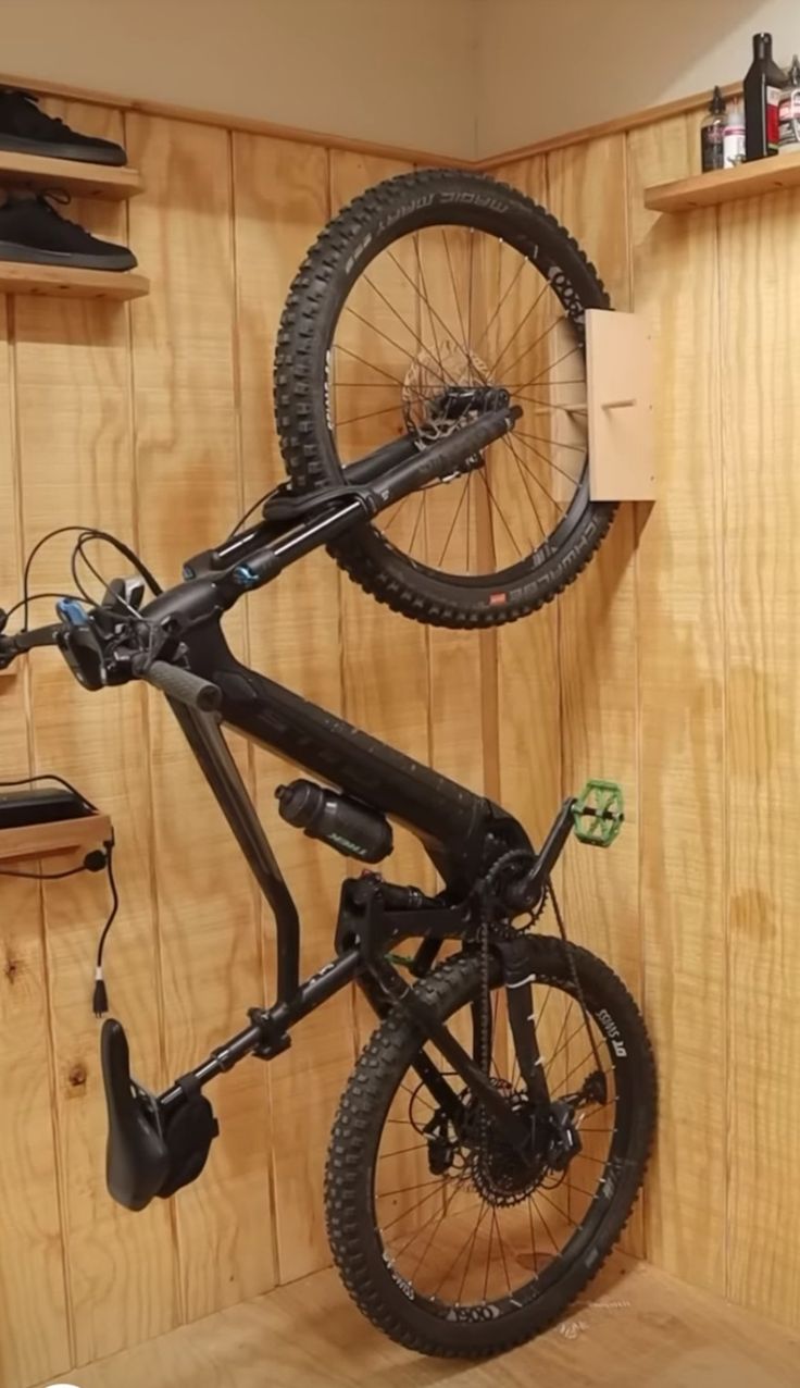 a bicycle is suspended upside down in a room with wood paneling and shelving