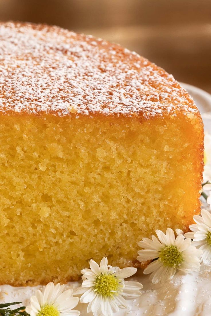 a piece of cake sitting on top of a white plate with daisies around it