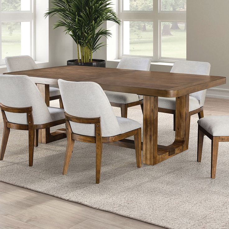 a dining room table with white chairs and a potted plant