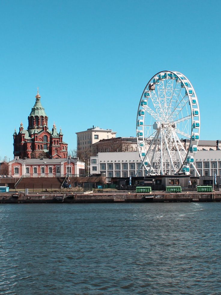 a large ferris wheel sitting on top of a river next to a tall city building