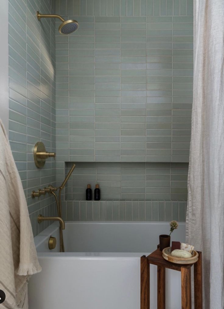 a white bath tub sitting next to a wooden stand with towels on top of it