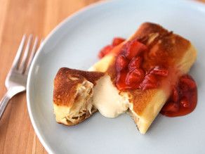 a white plate topped with two pieces of cake covered in strawberry compote sauce