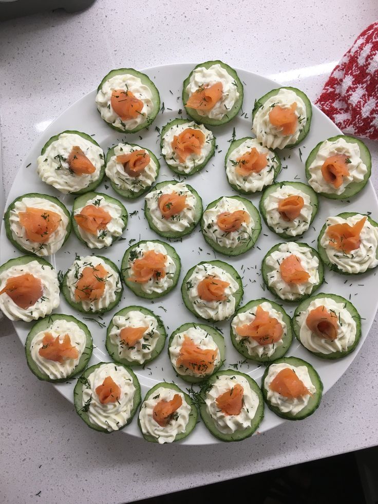 small cucumbers with cream cheese and salmon on them are arranged on a white plate