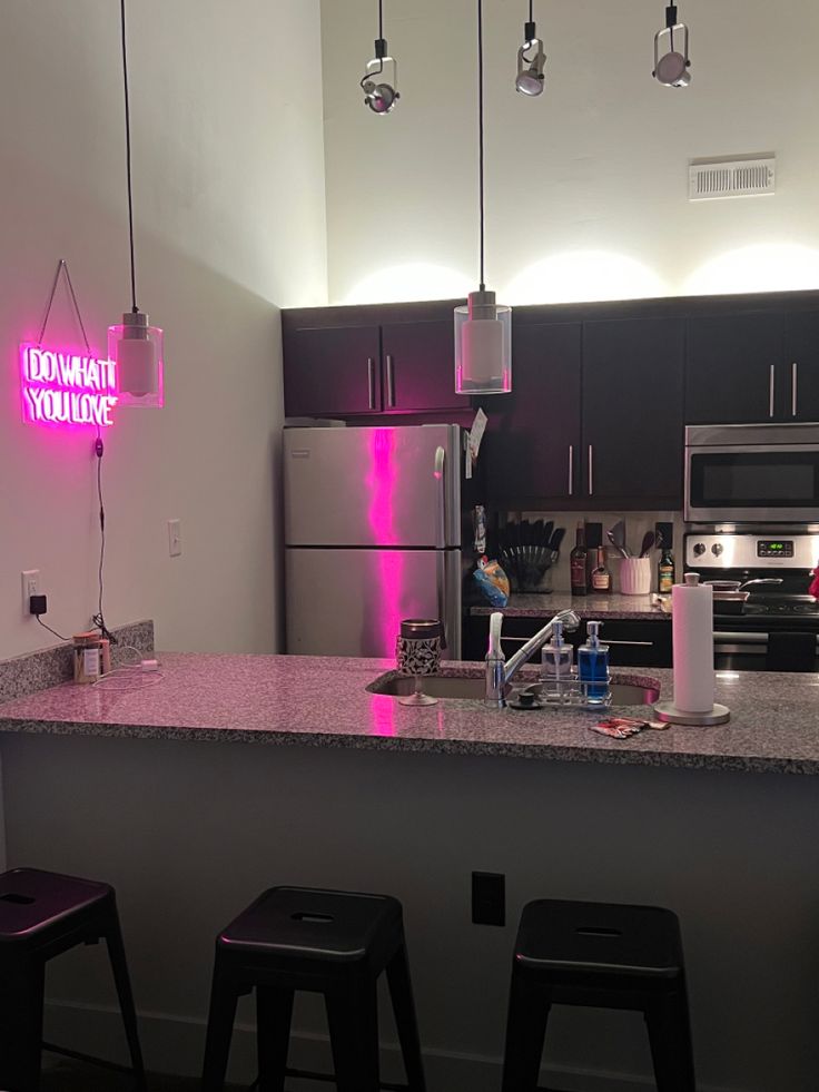 a kitchen with three stools next to a counter top and a refrigerator freezer