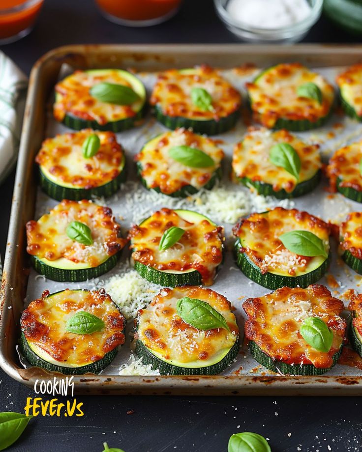 a baking pan filled with zucchini and cheeses on top of a table