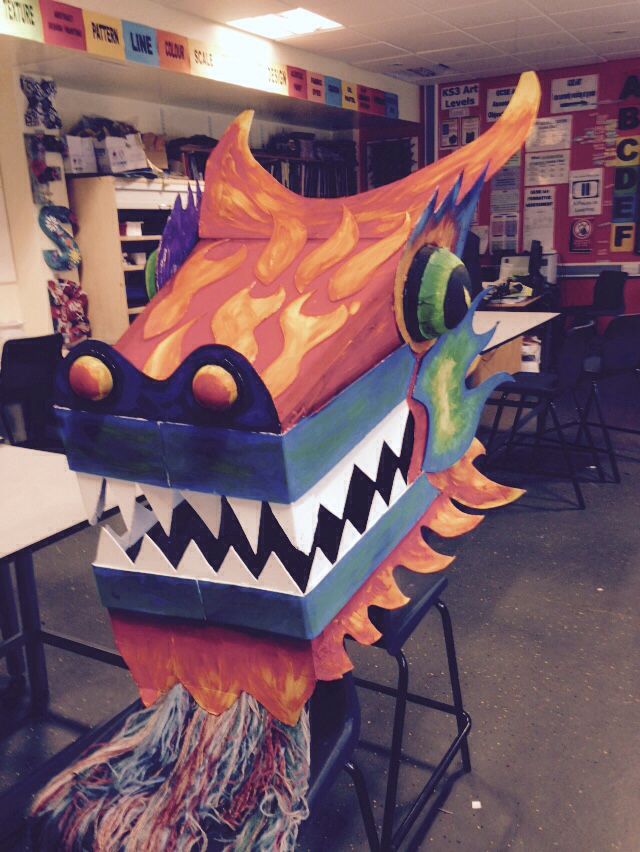 a dragon mask sitting on top of a chair in a room filled with desks