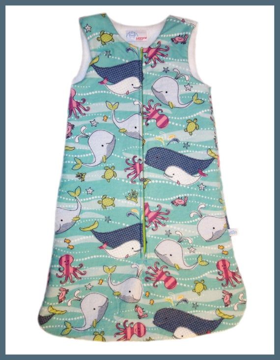 a baby sleeping bag with an image of whales and sea animals on the blue background