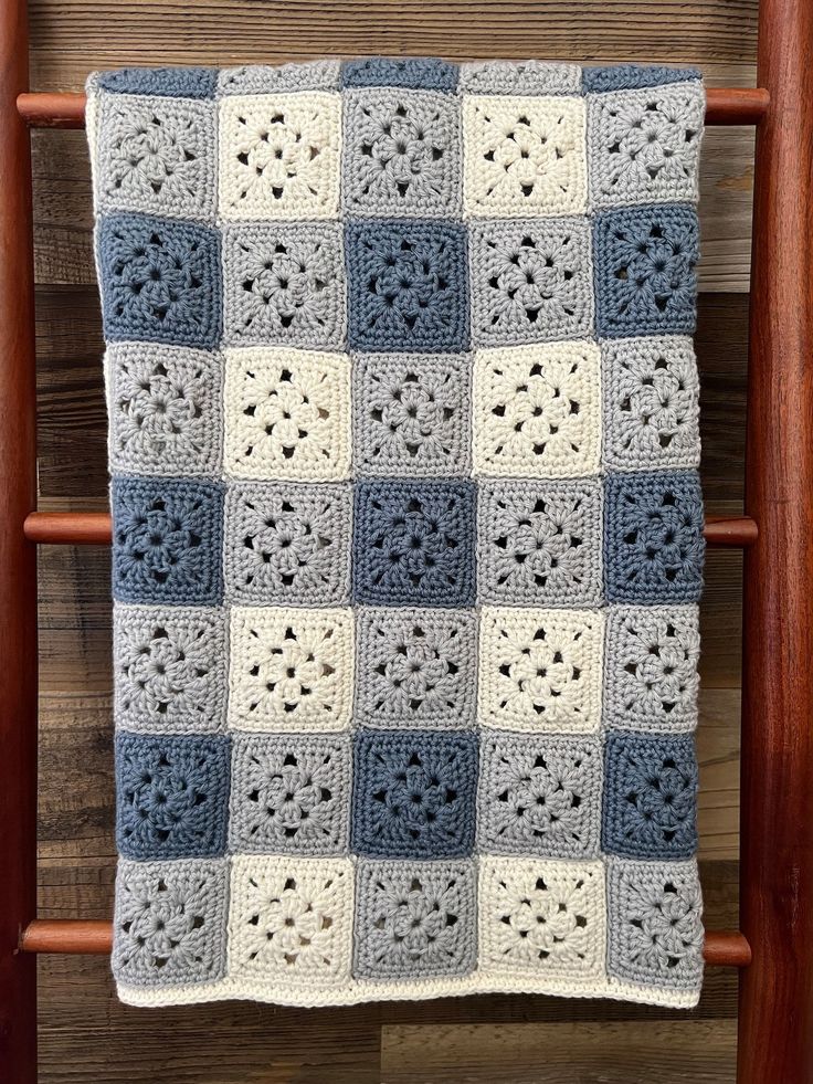 a blue and white crocheted blanket sitting on top of a wooden chair