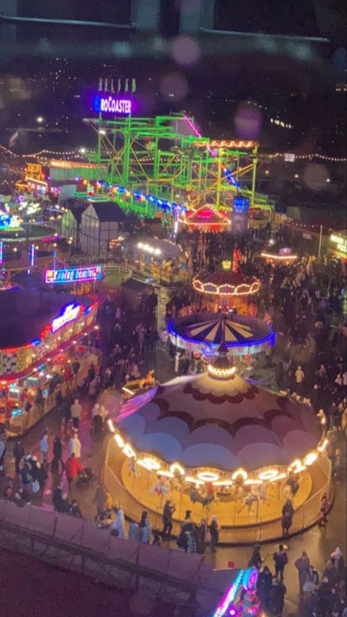 an aerial view of a fairground at night with lights on the carousels and rides