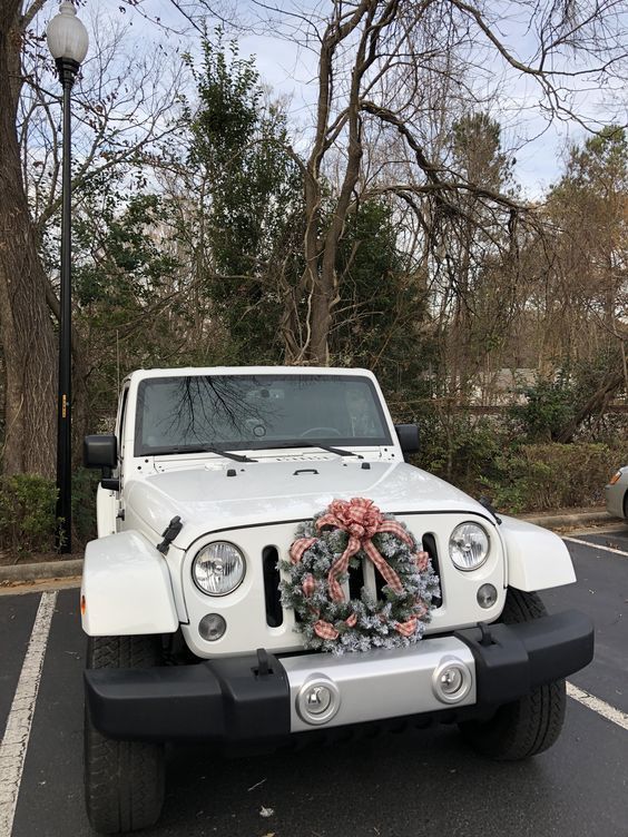 a white jeep parked in a parking lot with a wreath on the front of it