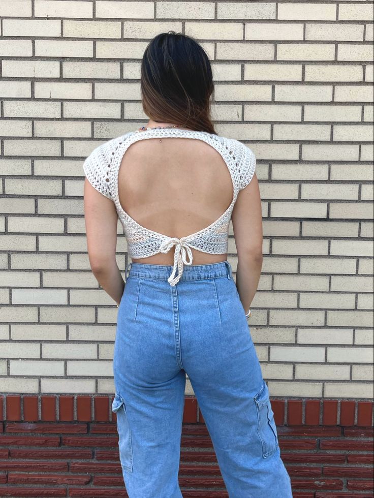 a woman standing in front of a brick wall with her back turned to the camera