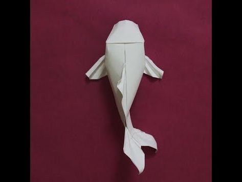 an origami fish made out of white paper on a red background with the bottom half folded up