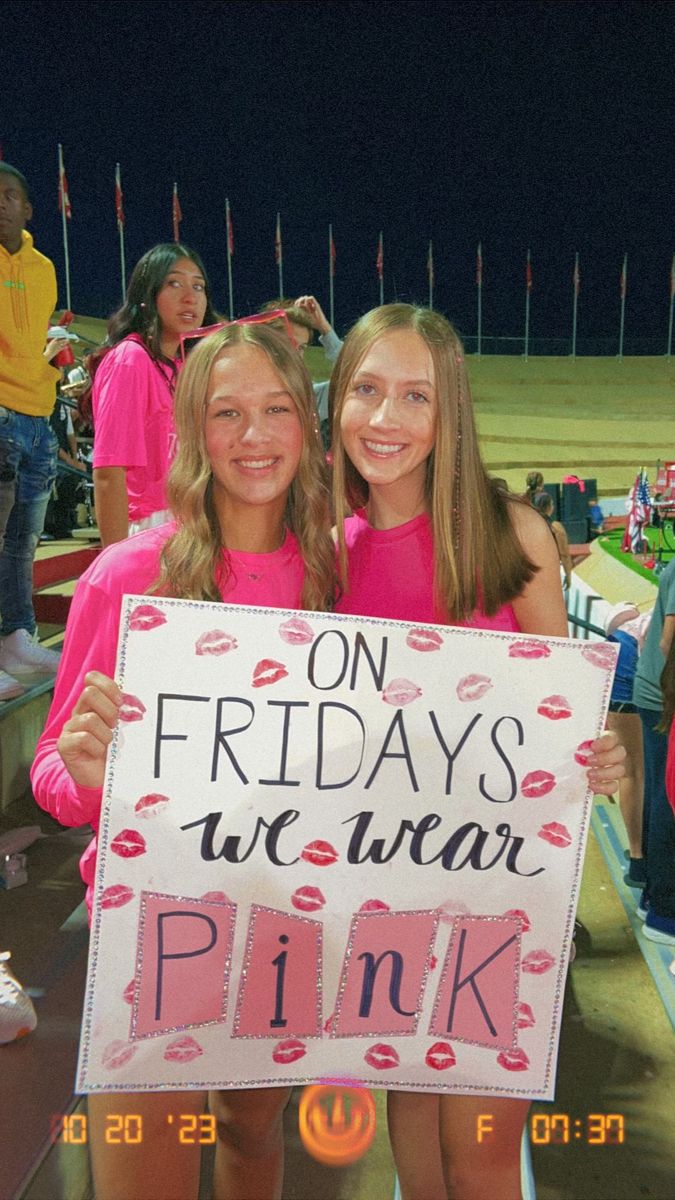 two girls holding up a sign that says on friday's we wear pink