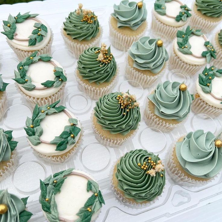 cupcakes decorated with green frosting and gold decorations on a white tablecloth