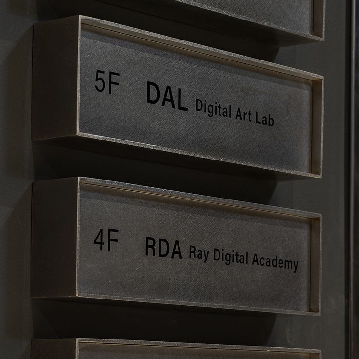 three metal signs that are on the side of a building with black lettering reading 5f, digital art lab and 4f rda ray digital academy