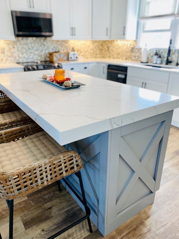 a kitchen island with two chairs in front of it and a bowl of fruit on the counter