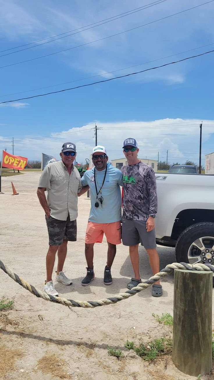 three men standing next to each other in front of a truck