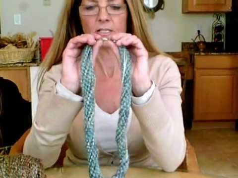 a woman sitting at a kitchen table holding two strands of rope in front of her face