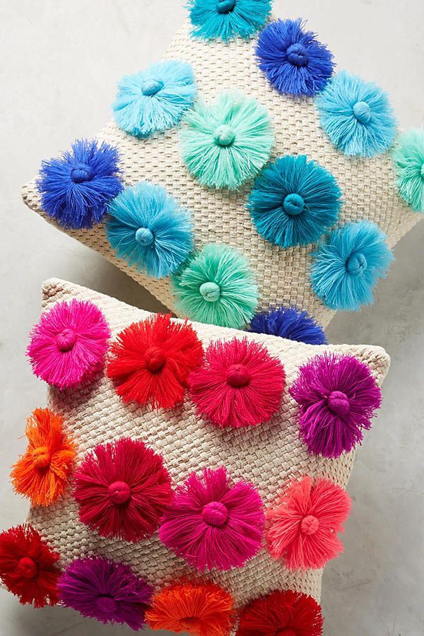 two colorful pillows with pom - poms on them