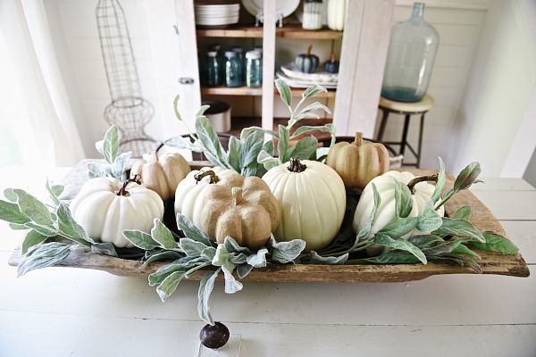 a wooden tray with pumpkins and greenery in it on a table top next to a window