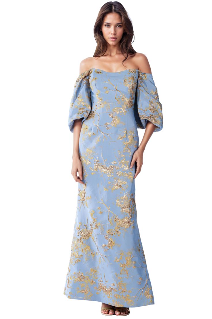 a woman wearing a blue dress with gold flowers on it and an off the shoulder top