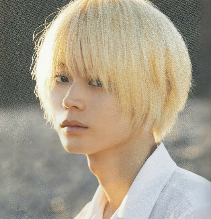 a young man with blonde hair wearing a white shirt and looking off to the side