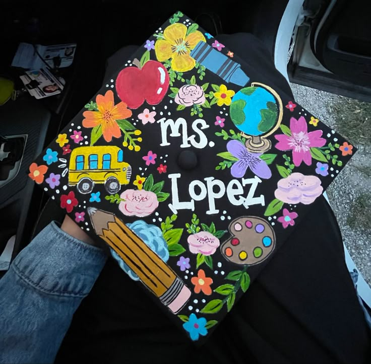 a person wearing a black graduation cap with colorful flowers and the words ms lopez on it