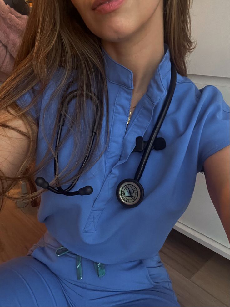 a woman wearing a blue scrub suit with a stethoscope on her neck