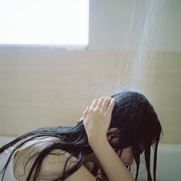 a woman is sitting in the bathtub with her head down and hair flowing out