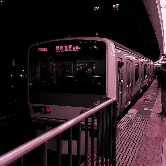 a subway train stopped at a station with people waiting on the platform for it to arrive