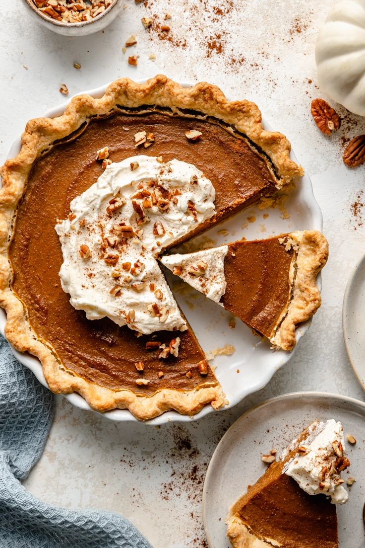 a slice of pumpkin pie with whipped cream and pecans on the side next to it