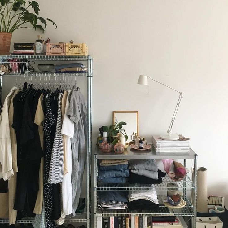 an organized closet with clothes, shoes and other items on shelves in front of a white wall