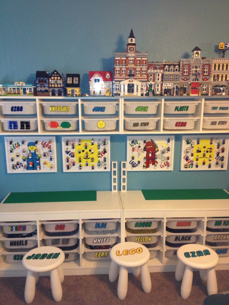 a room with legos on the wall and toy storage bins in front of it