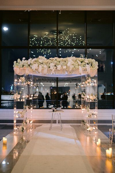 a wedding ceremony setup with candles and flowers on the floor in front of a large window