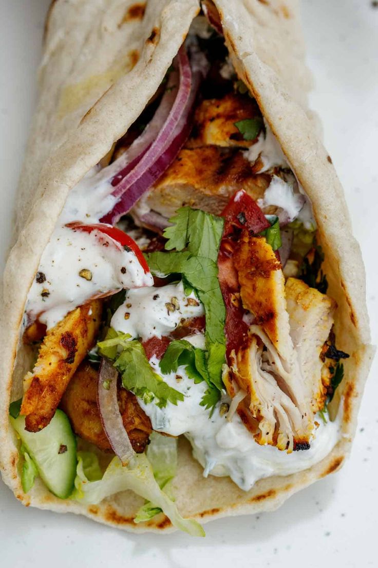 a pita filled with chicken, lettuce and onions