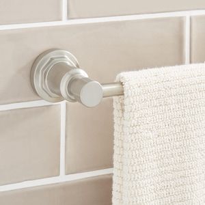 a close up of a towel rack on a wall with white tiles in the background