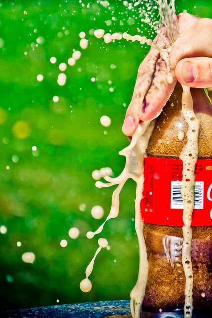 a person is pouring water onto a bottle with the word stop written on it and splashing from its top