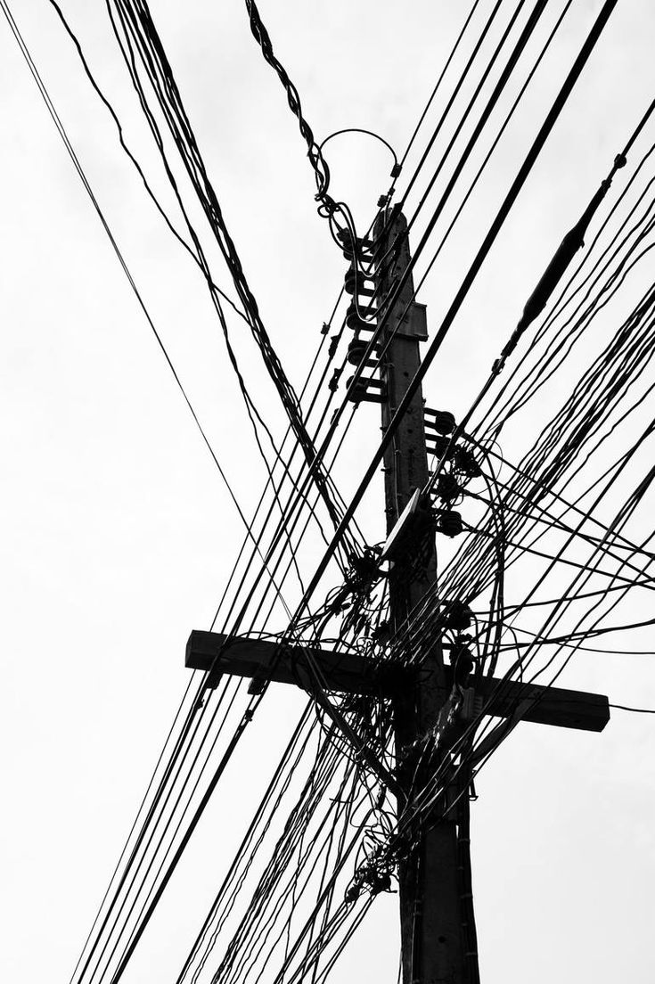 black and white photograph of an electric pole with many wires on it's sides