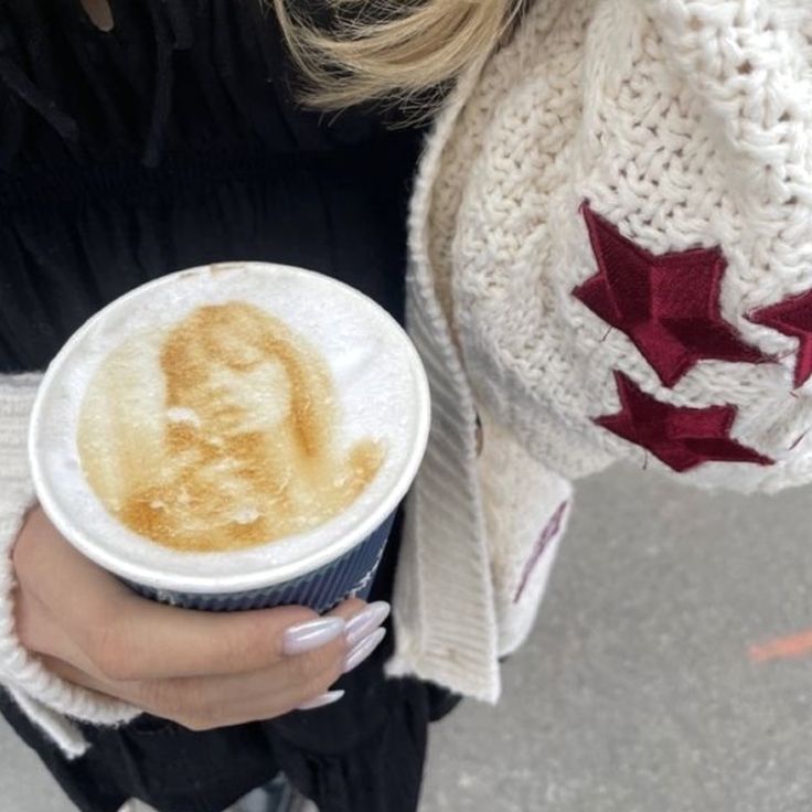 a close up of a person holding a cup of coffee with an image on it