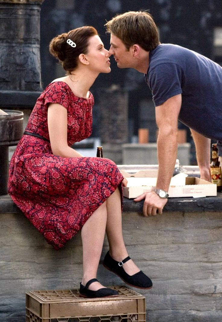 a man kissing a woman on the cheek as they sit next to each other in front of a fountain