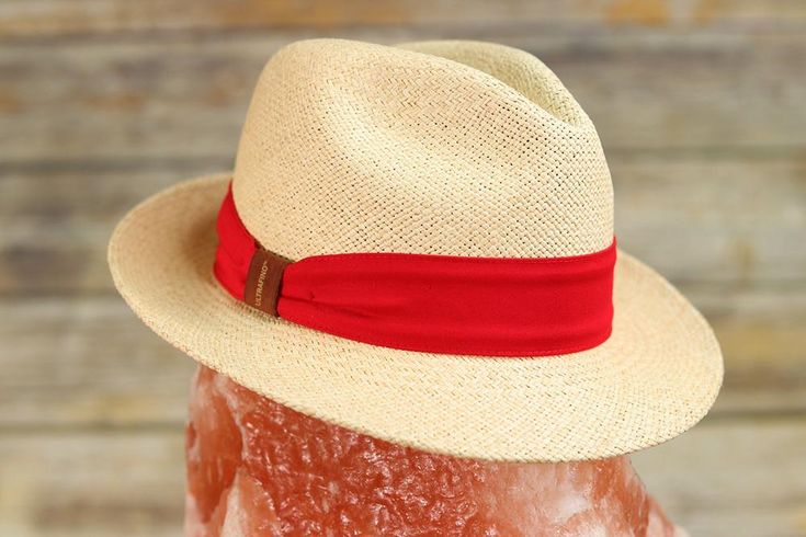 A modern take on the classic fedora Traveler made with 100% toquilla straw and pink or red hatband with leather bow detailing. This effortless piece can easily be worn year-round. The quality can be seen in the beautifully structured crown and stingy brim. This packable fedora is meant for traveling with you wherever you go whether in a suitcase, a purse, or a beach bag. This item is a genuine Panama hat handwoven in Ecuador and blocked and trimmed in the USA. Imported.Crown: 4 1/4" Center DentM Packable Hat, Hat Boxes, Leather Bow, Quality Hats, Leather Bows, Beautiful Hats, Hat Band, Hat Making, Hat Sizes