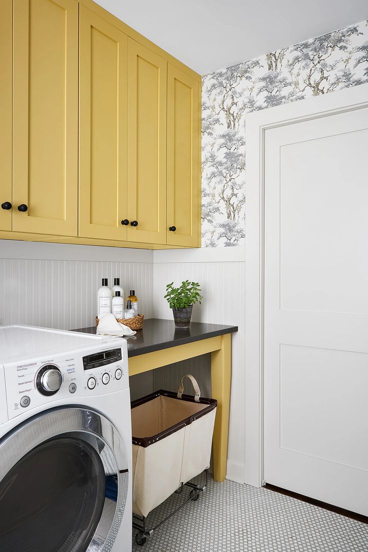 a washer and dryer in a small room with yellow cabinets on the wall