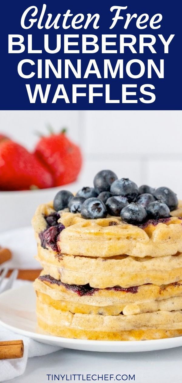 a stack of blueberry cinnamon waffles on a white plate with strawberries in the background