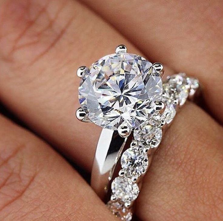 a woman's hand with a diamond ring on top of her finger and an engagement band