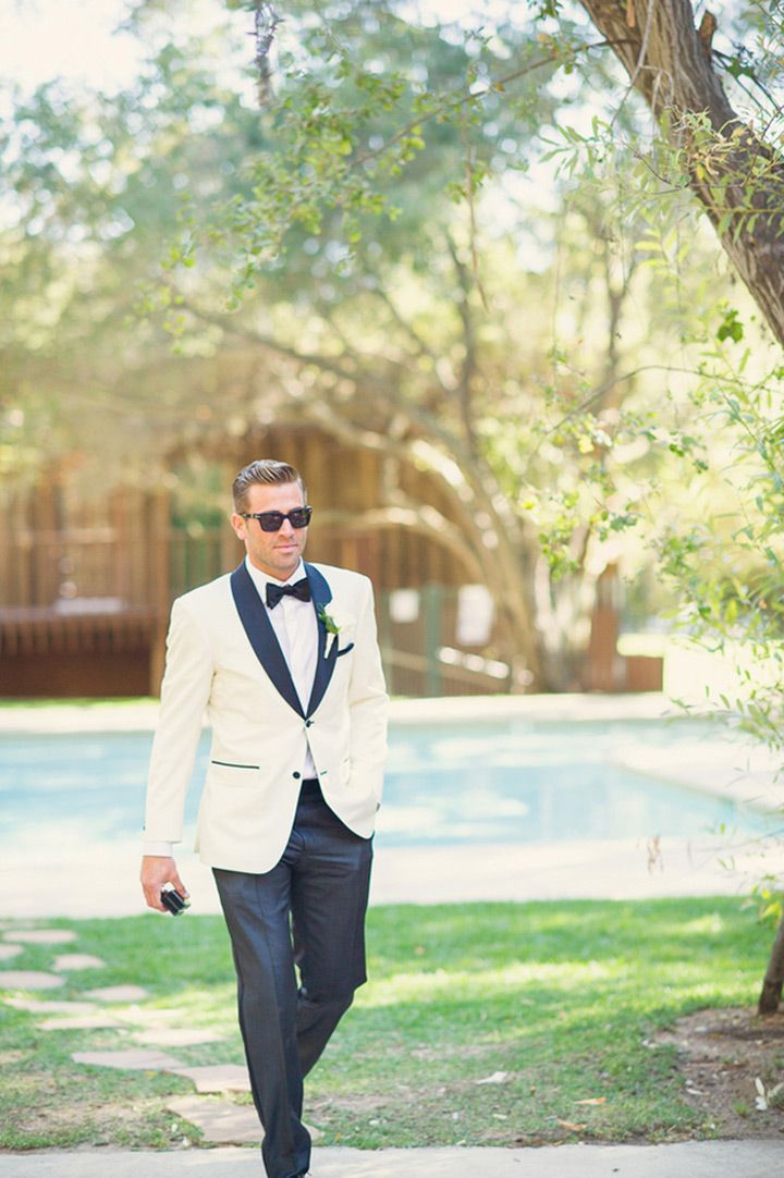 a man in a tuxedo and sunglasses walking down the sidewalk near a pool