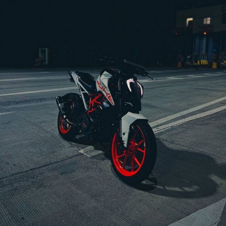 the motorcycle is parked on the street in the parking lot at night with bright red rims