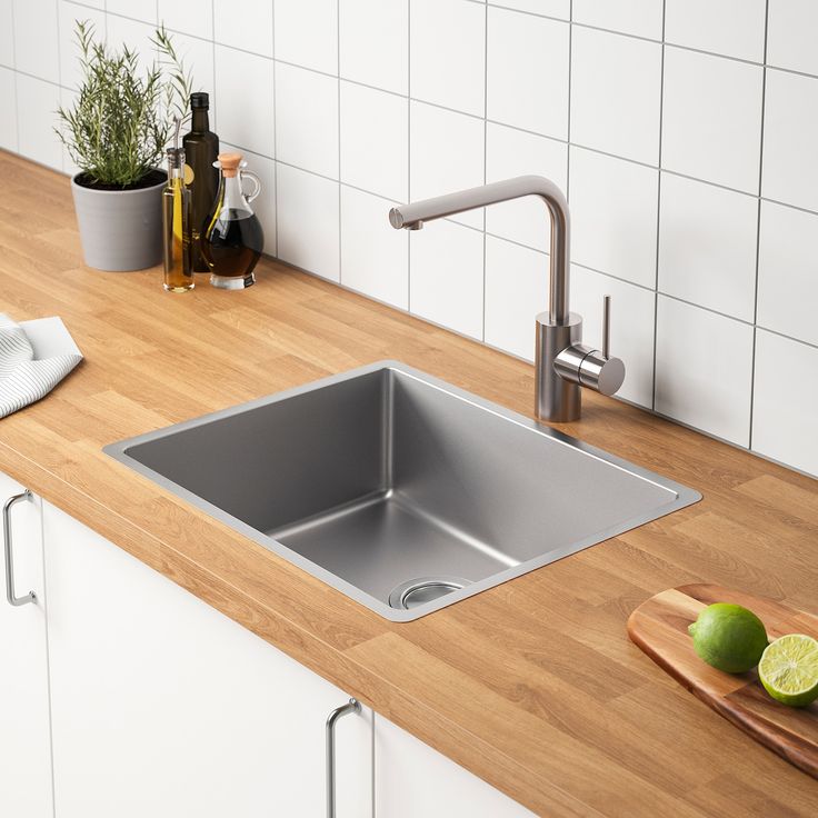 a kitchen sink sitting on top of a wooden counter next to a cutting board and knife