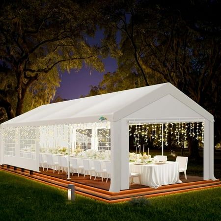 a white tent set up with tables and chairs for an outdoor dinner party at night