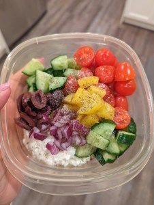 a person holding a plastic container filled with different types of vegetables and rice in it